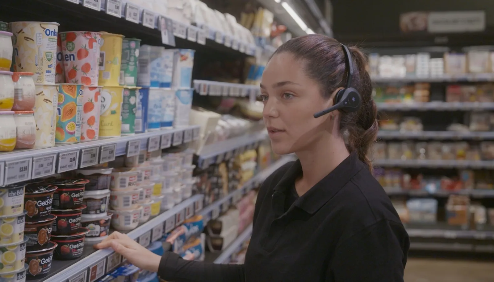 Associate in a Pro12 headset checking the dairy aisle